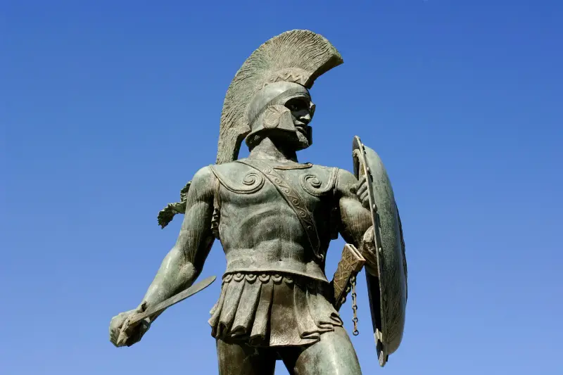 The bronze statue of King Leonidas at Thermopylae, helmeted and holding his shield and sword against a clear blue sky
