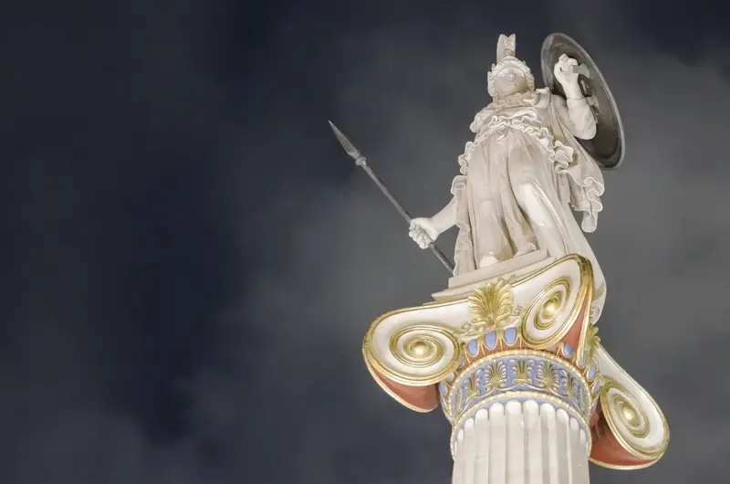 A statue of the goddess Athena atop an ornate column outside the Academy of Athens, lit up against a dark sky