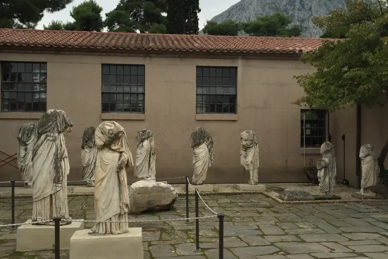 Headless draped statues arranged in the open courtyard of the Ancient Corinth museum
