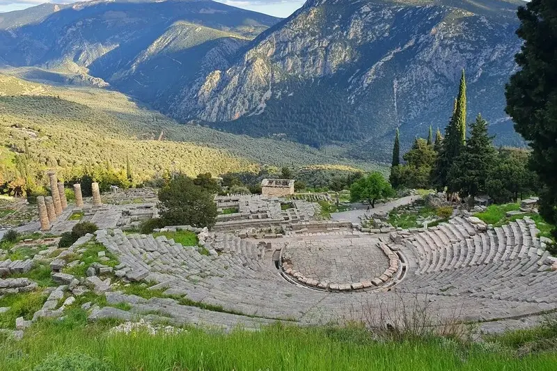 The ancient theatre and ruins of Delphi set into the mountainside, with the Pleistos valley spreading out below
