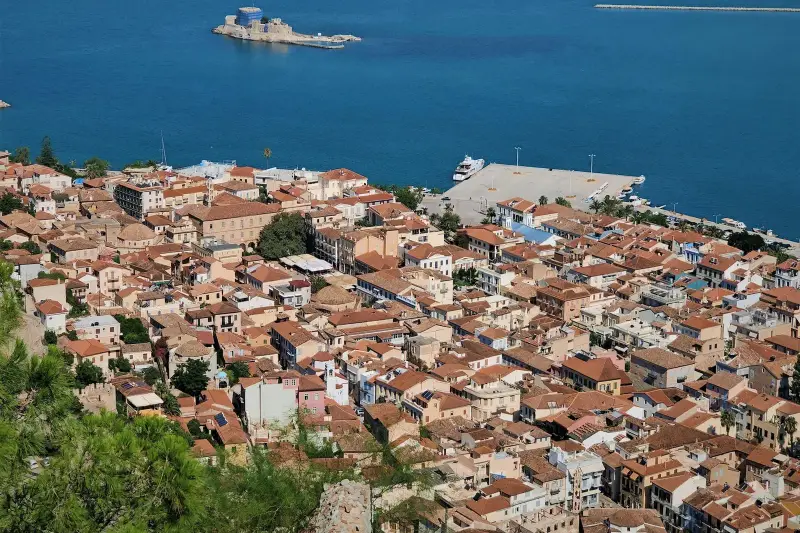 An elevated view over Nafplio's red-tiled old town to the harbour, with the small island fortress of Bourtzi offshore