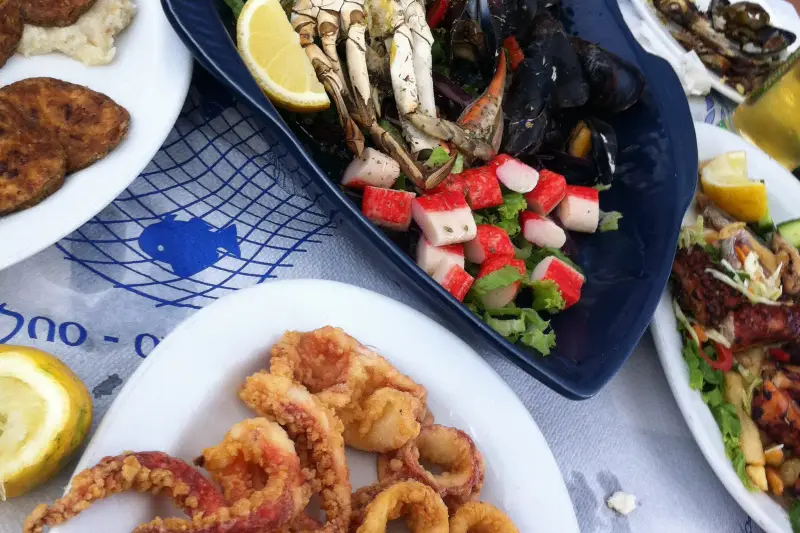 A seafood platter of mussels and crab beside a plate of fried calamari rings
