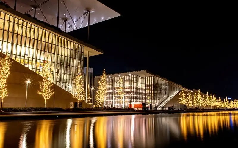 The Stavros Niarchos Foundation Cultural Center lit with Christmas lights and reflected in its canal at night