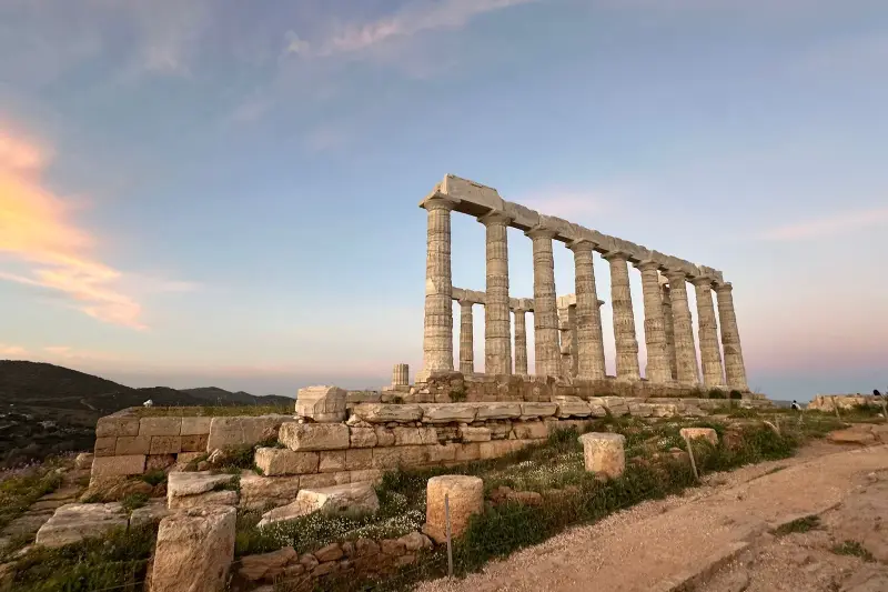 The Temple of Poseidon at Cape Sounion, its marble columns lit gold by the setting sun